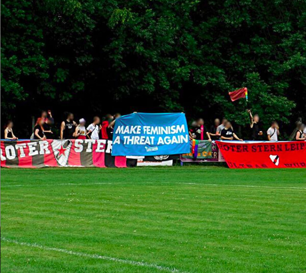 Fan-Kurve des Roten Stern Leipzig mit einem Transparent mit der Aufschrift "MAKE FEMINISM A THREAT AGAIN!"